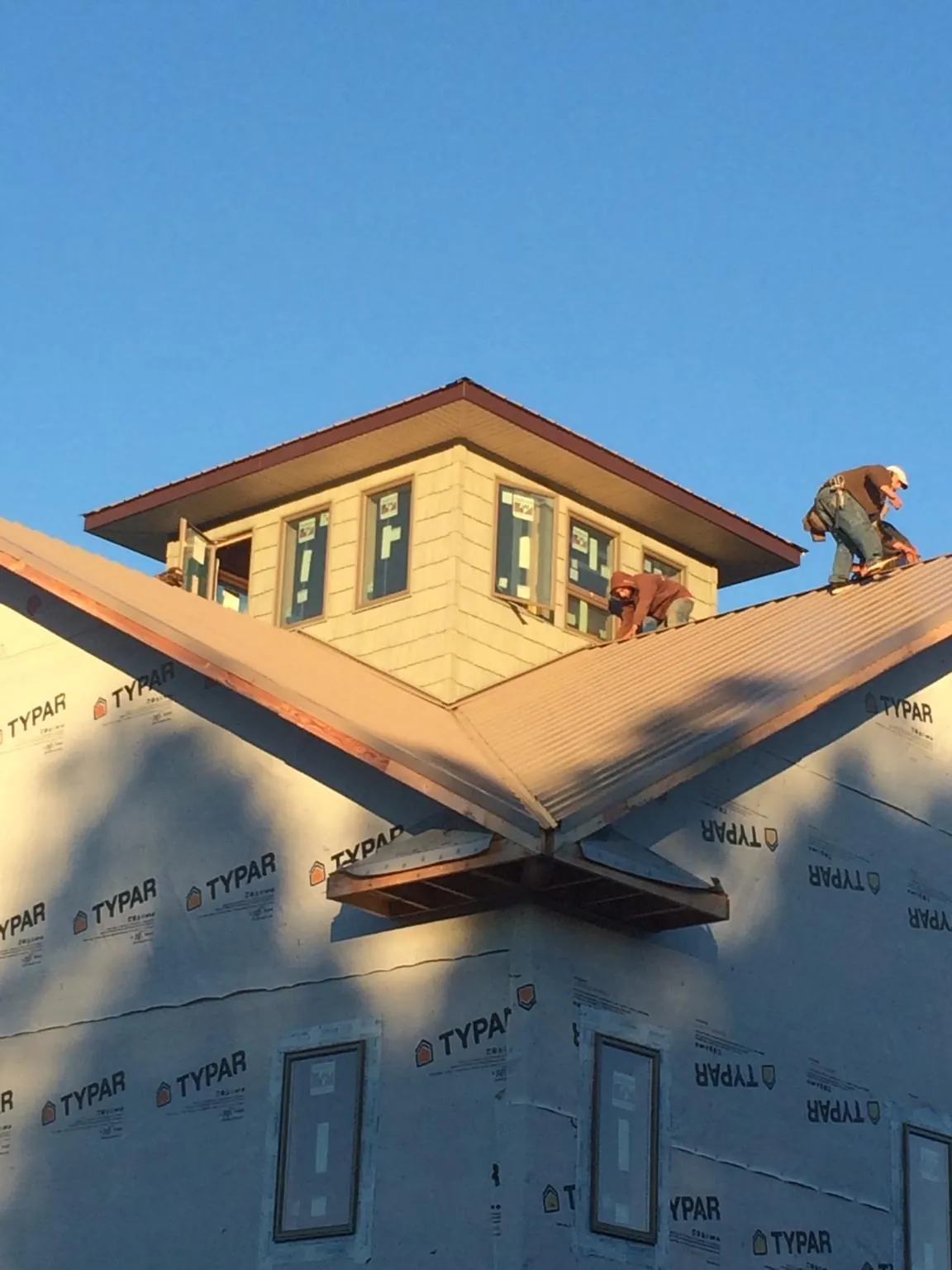 Roofers working around a rooftop cupola on a new metal roof at sunset — Roof Waterproofing in Weston by Roofing Brothers